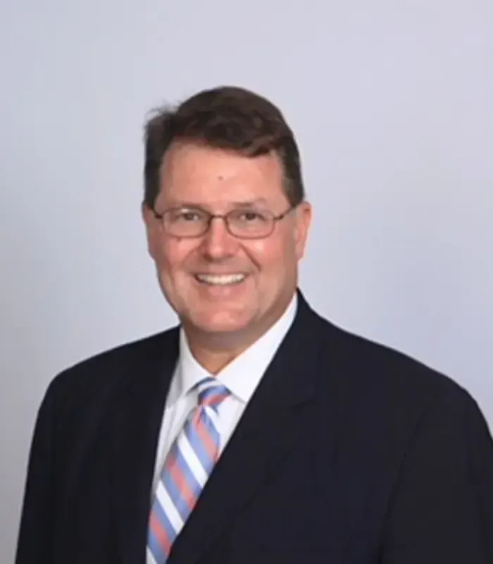 A man in a suit and tie is smiling for the camera