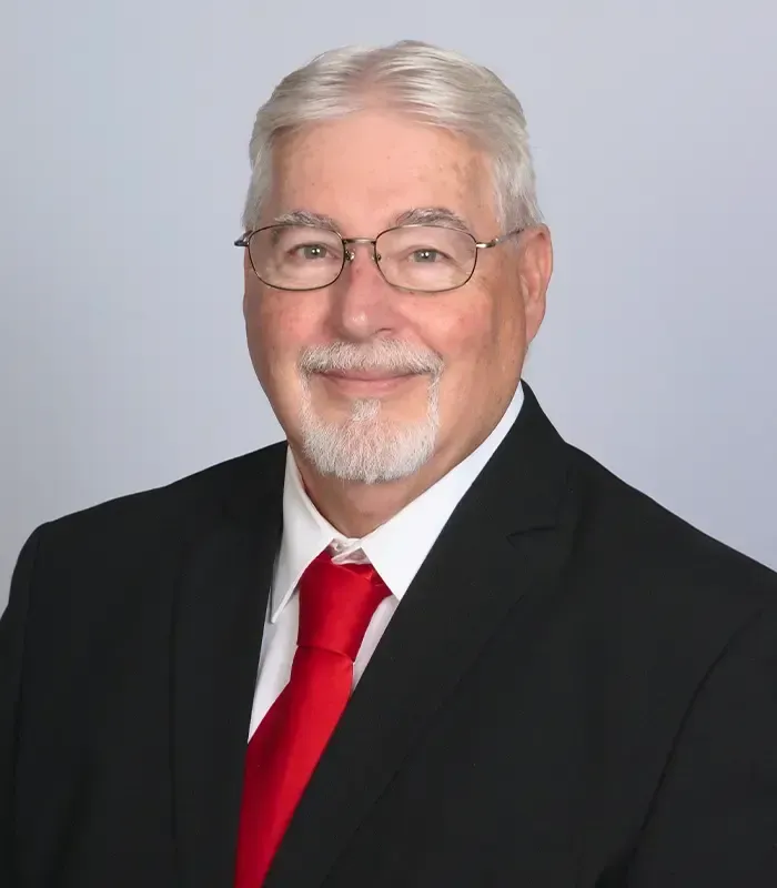 A man in a suit and red tie is smiling for the camera