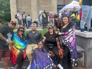 A group of people wearing butterfly wings posing for a photo on stone steps outside a building.