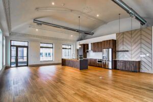 Spacious, modern kitchen with hardwood floors, dark wood cabinets, stainless steel appliances, and high vaulted ceilings.
