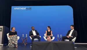 Four panelists sit in white chairs on a stage with a large blue screen featuring the Apartmentalize logo.