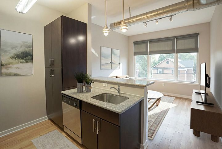 Bright modern kitchen with dark cabinets, granite island, pendant lights, and a windowed dining nook