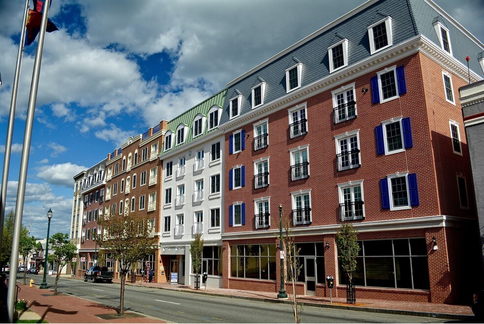 Street view of a row of red, white, and brown brick buildings under a blue sky with clouds