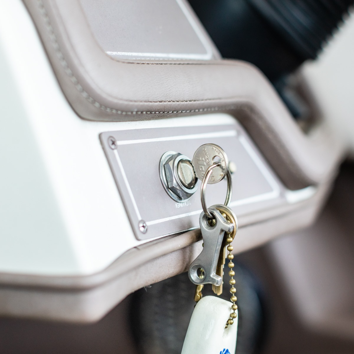 Close-up of ignition with keys hanging. Silver panel, tan car interior.