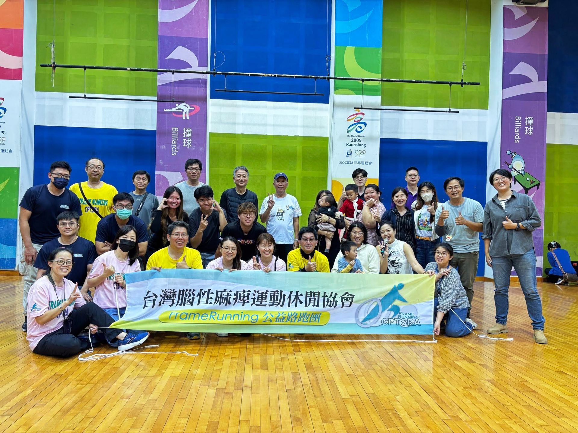 無框架運動活動合影：台灣腦性麻痺運動休閒協會大合照，參與者與家長拉著布條在體育館內歡聚，展現陪伴病友參與復健體用的意義。
