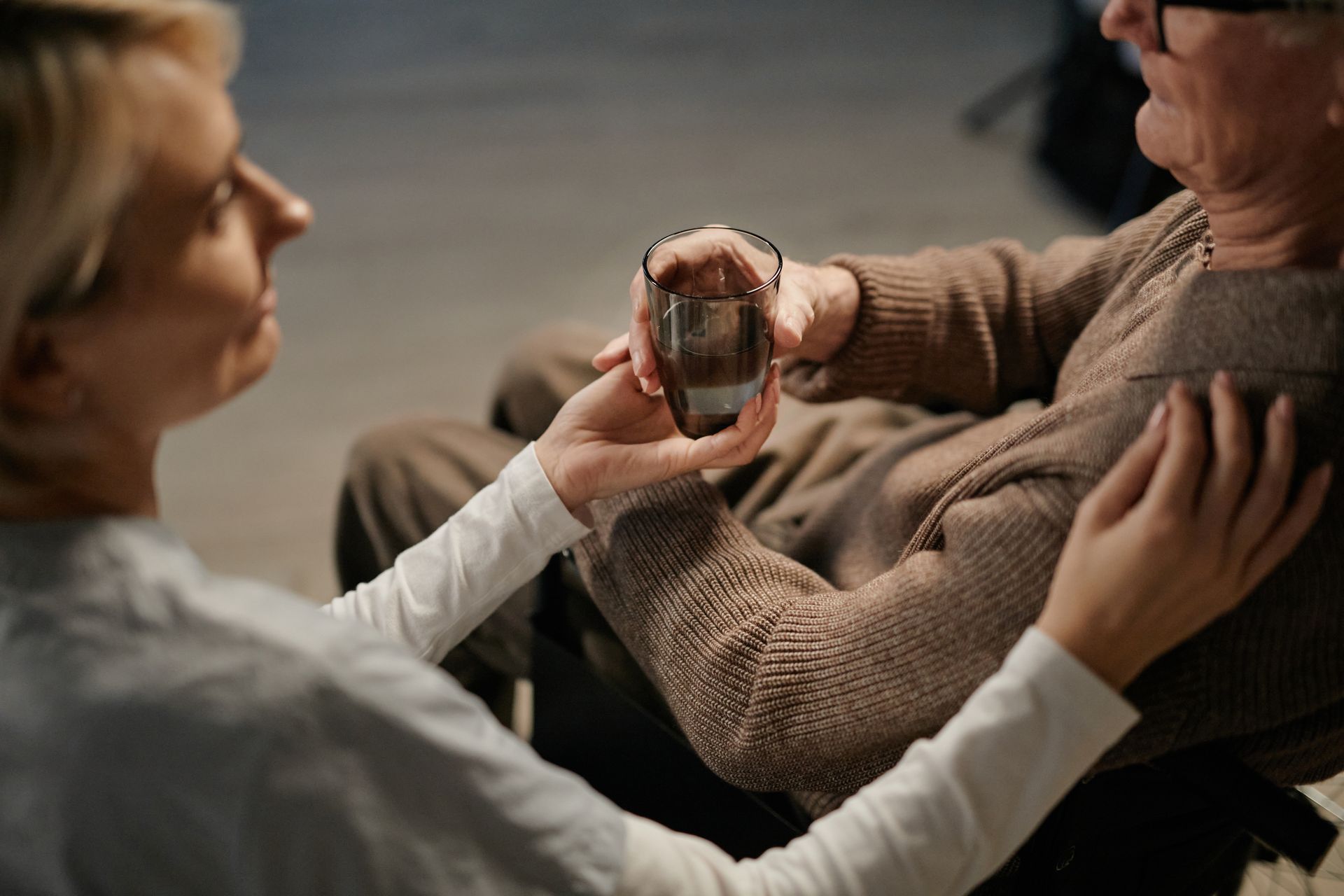 Caregiver offering a glass of water to an elderly man at home in San Diego CA