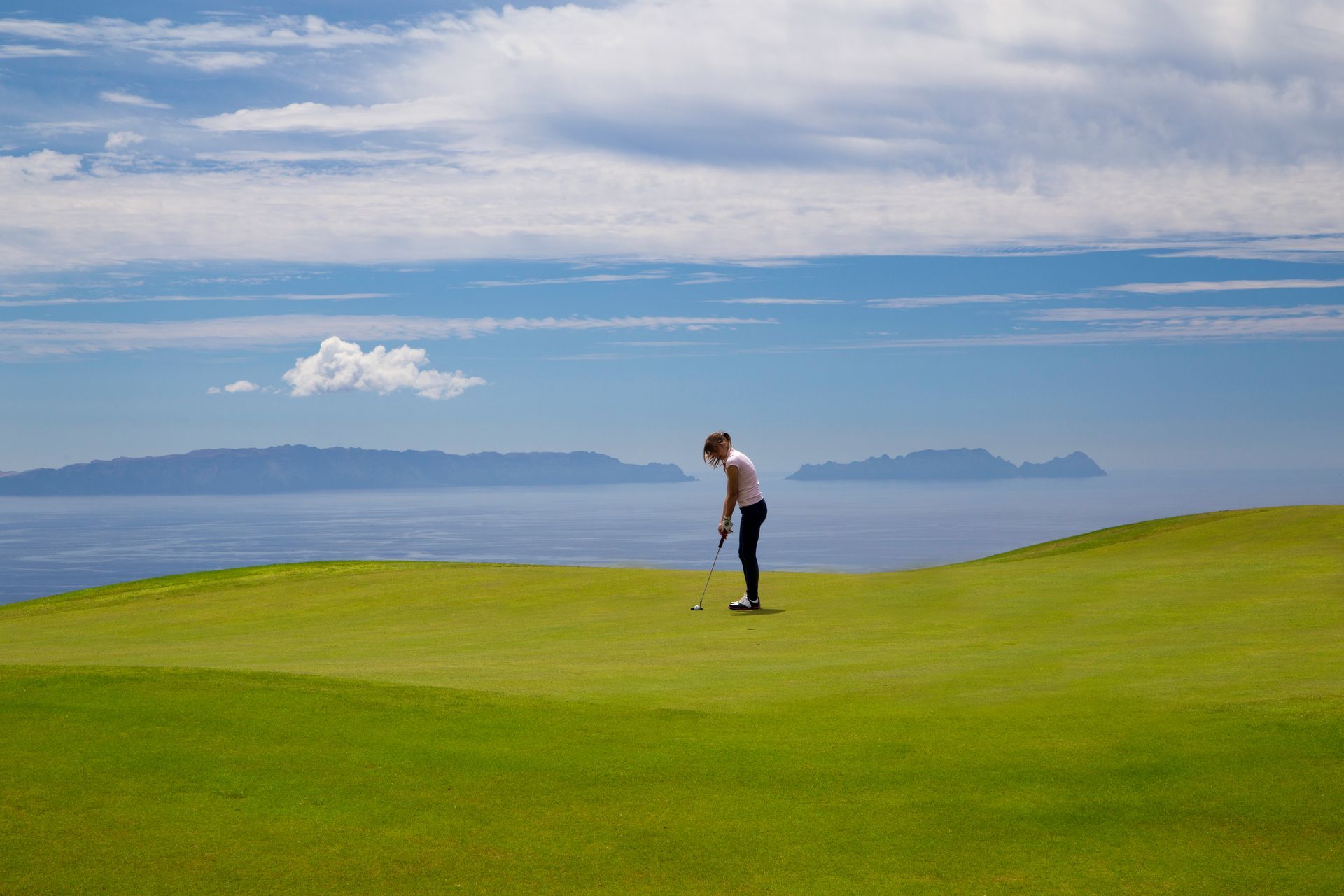 A man is putting a golf ball on a golf course.