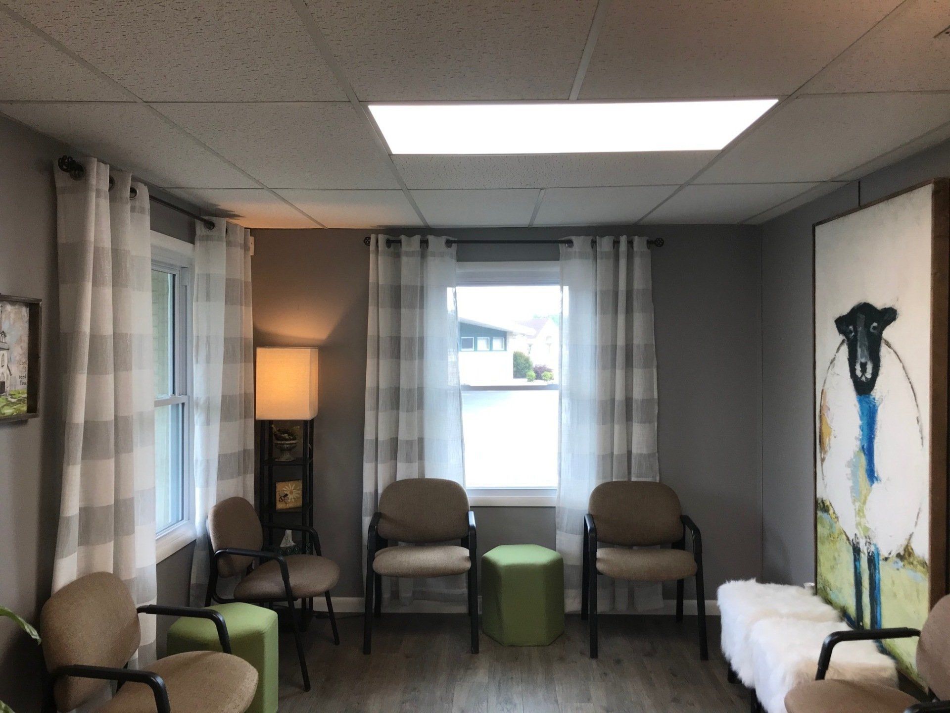 Waiting room with chairs, windows, and decorative art. Gray and white color scheme.