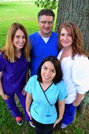 Medical staff in scrubs pose outdoors.