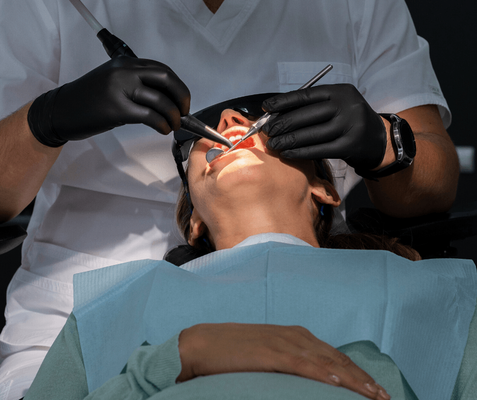 Dentist using tools on a patient in a dental chair. Patient has protective eyewear.