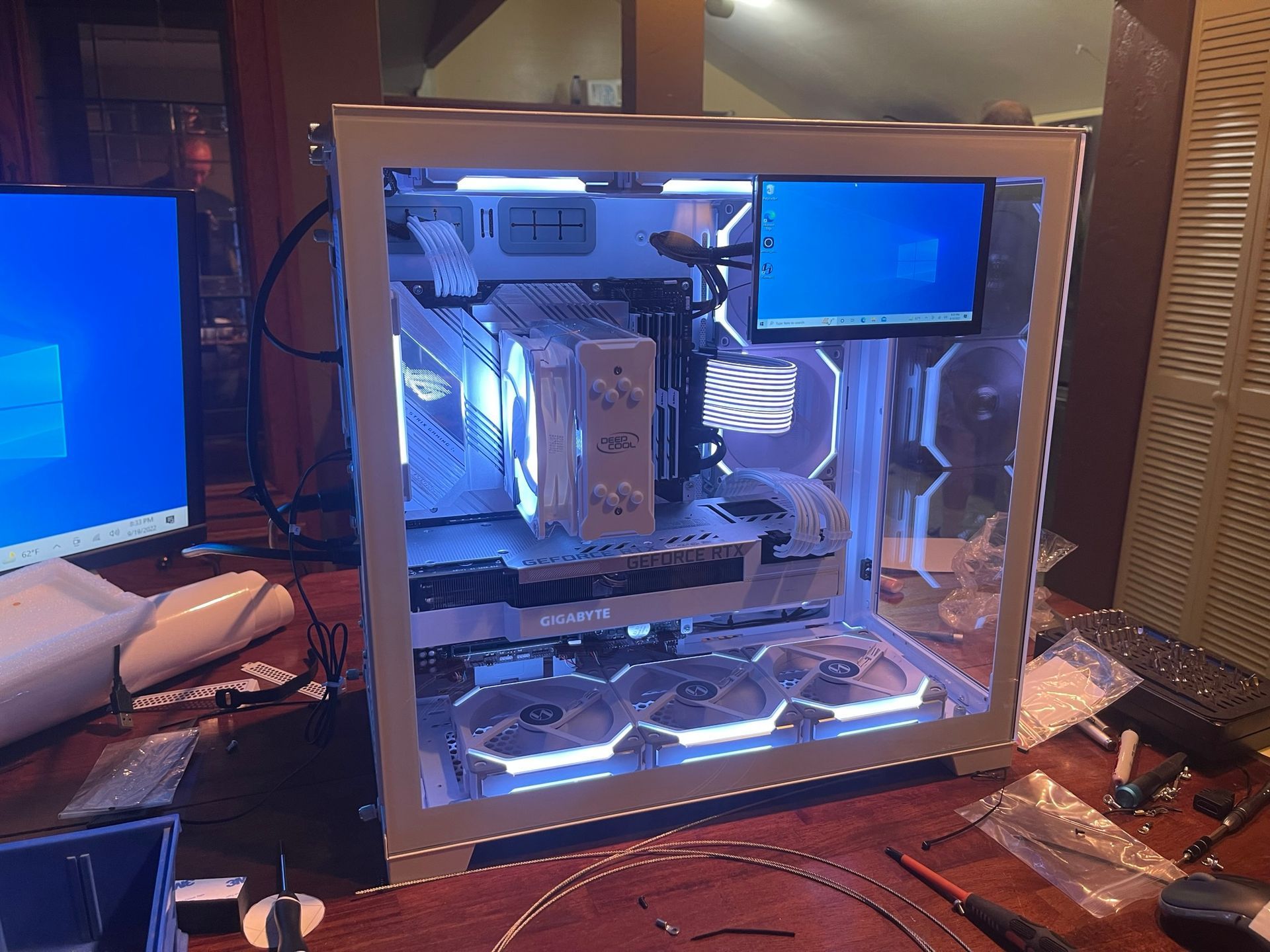 Desktop PC tower with transparent side panel glowing blue inside a room