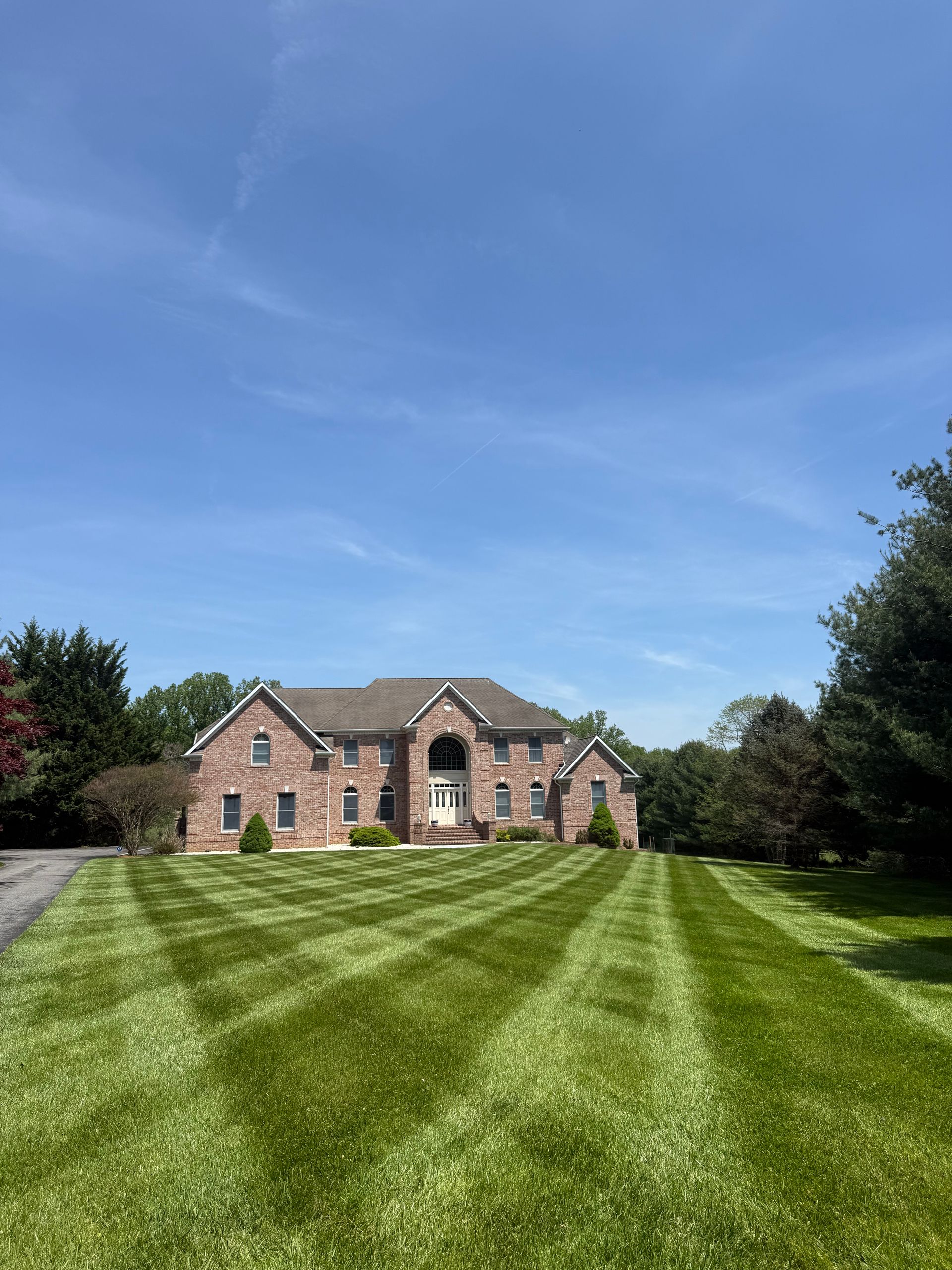 Brick house with a wide striped lawn under a clear blue sky
