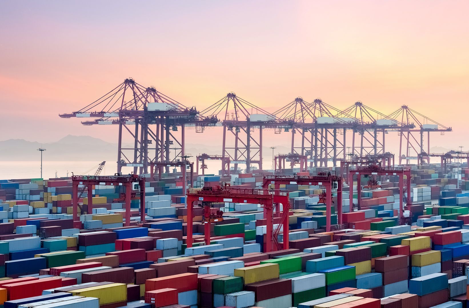 Porto de contêineres com contêineres empilhados e guindastes ao pôr do sol