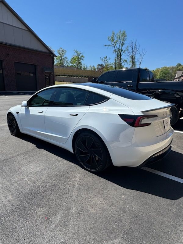 White Tesla sedan parked beside a building on a sunny day