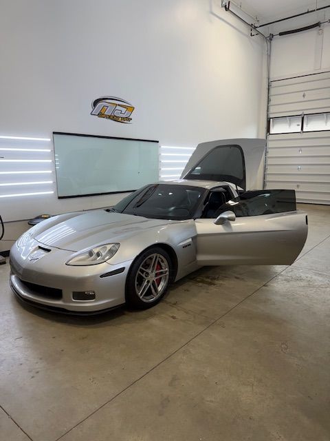Silver sports car in a garage with one door open and rear hatch raised