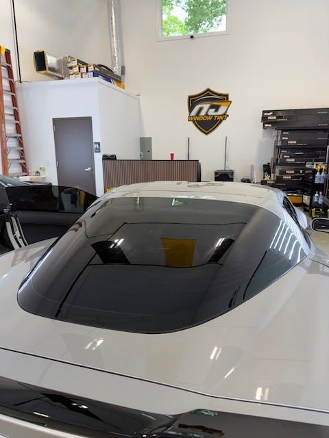 White sports car in a workshop garage with shelves and a wall logo.