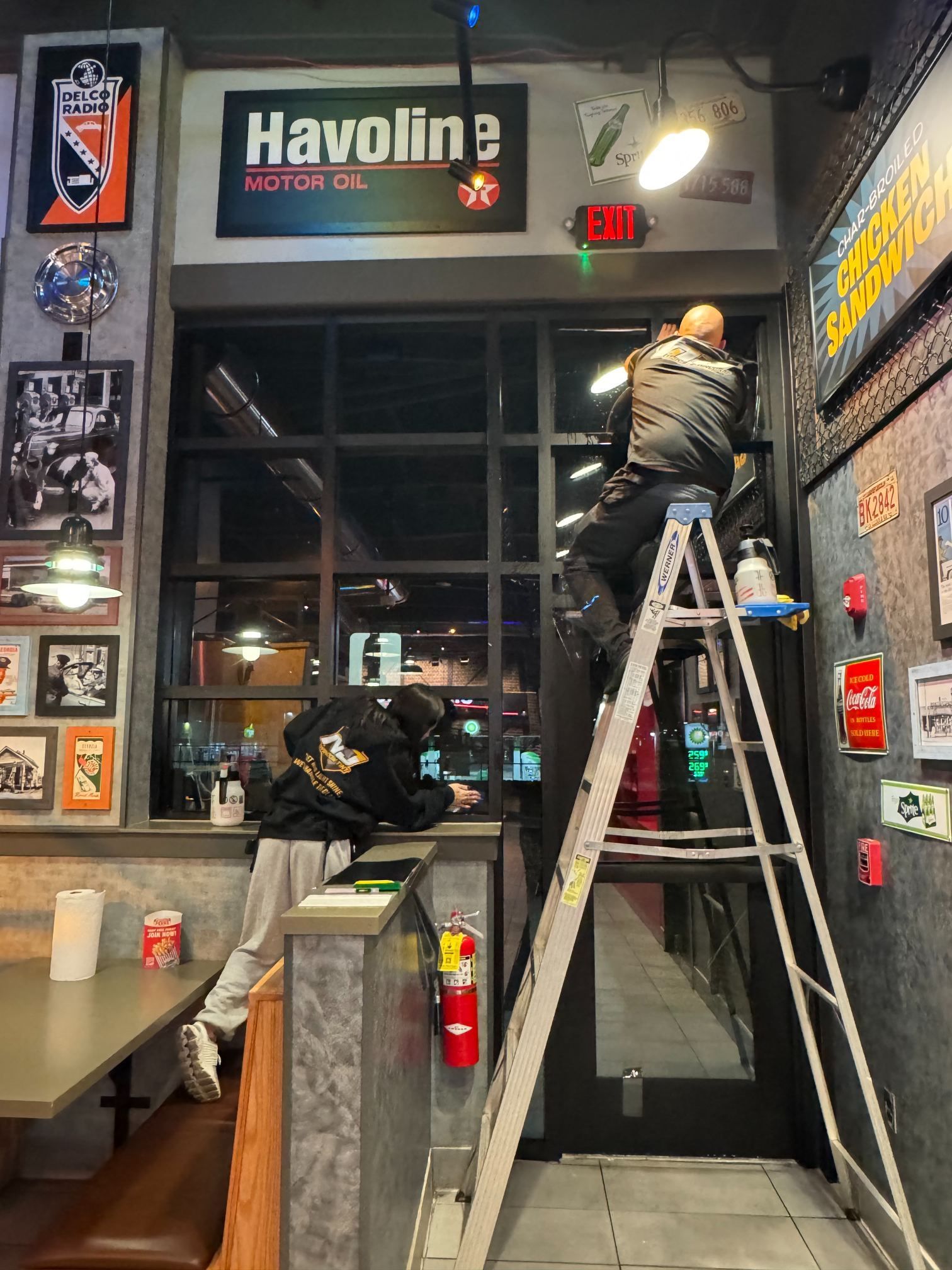 Workers on ladders installing lights in a garage-style entryway with a Haviline sign above.