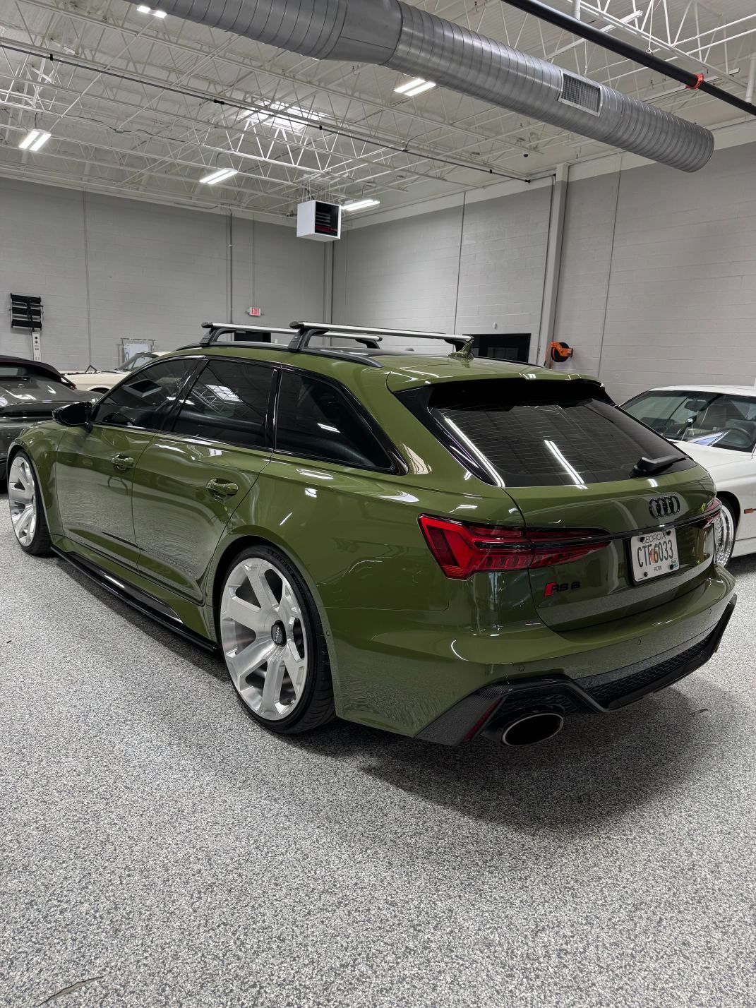 Green Audi sedan parked in a bright showroom with speckled gray flooring