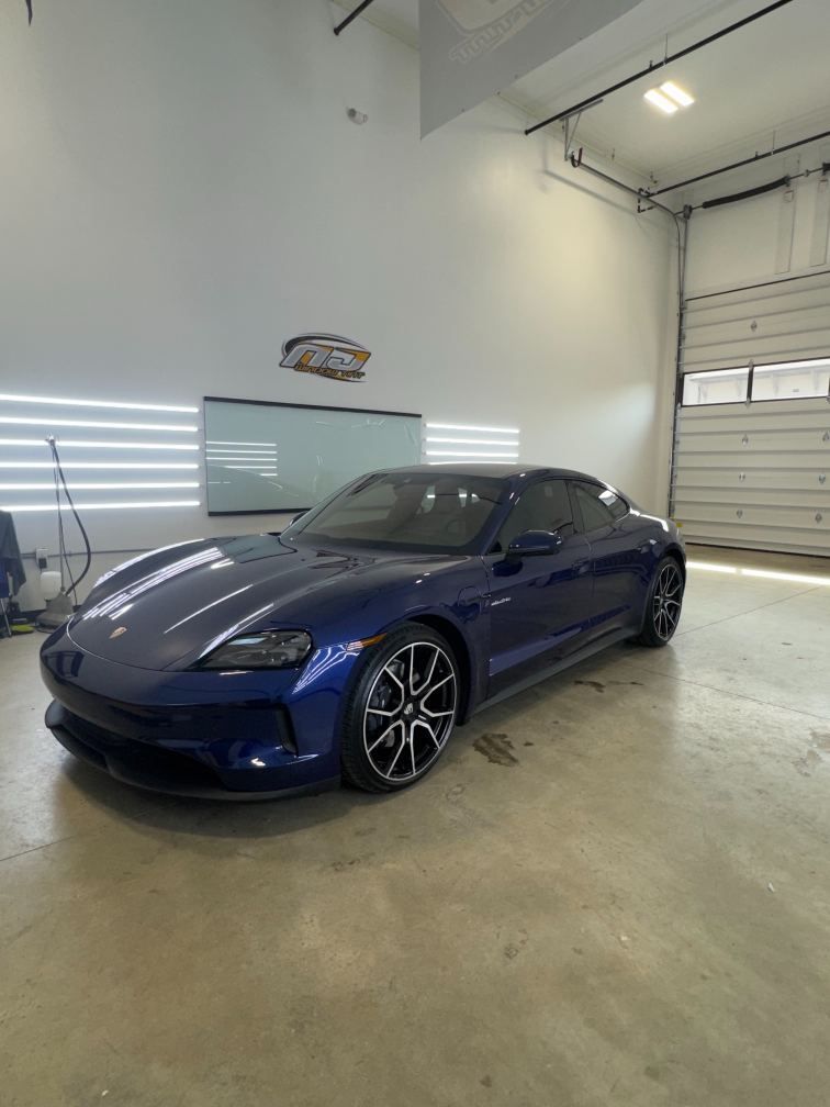 Blue sports car parked inside a garage with white walls and concrete floor