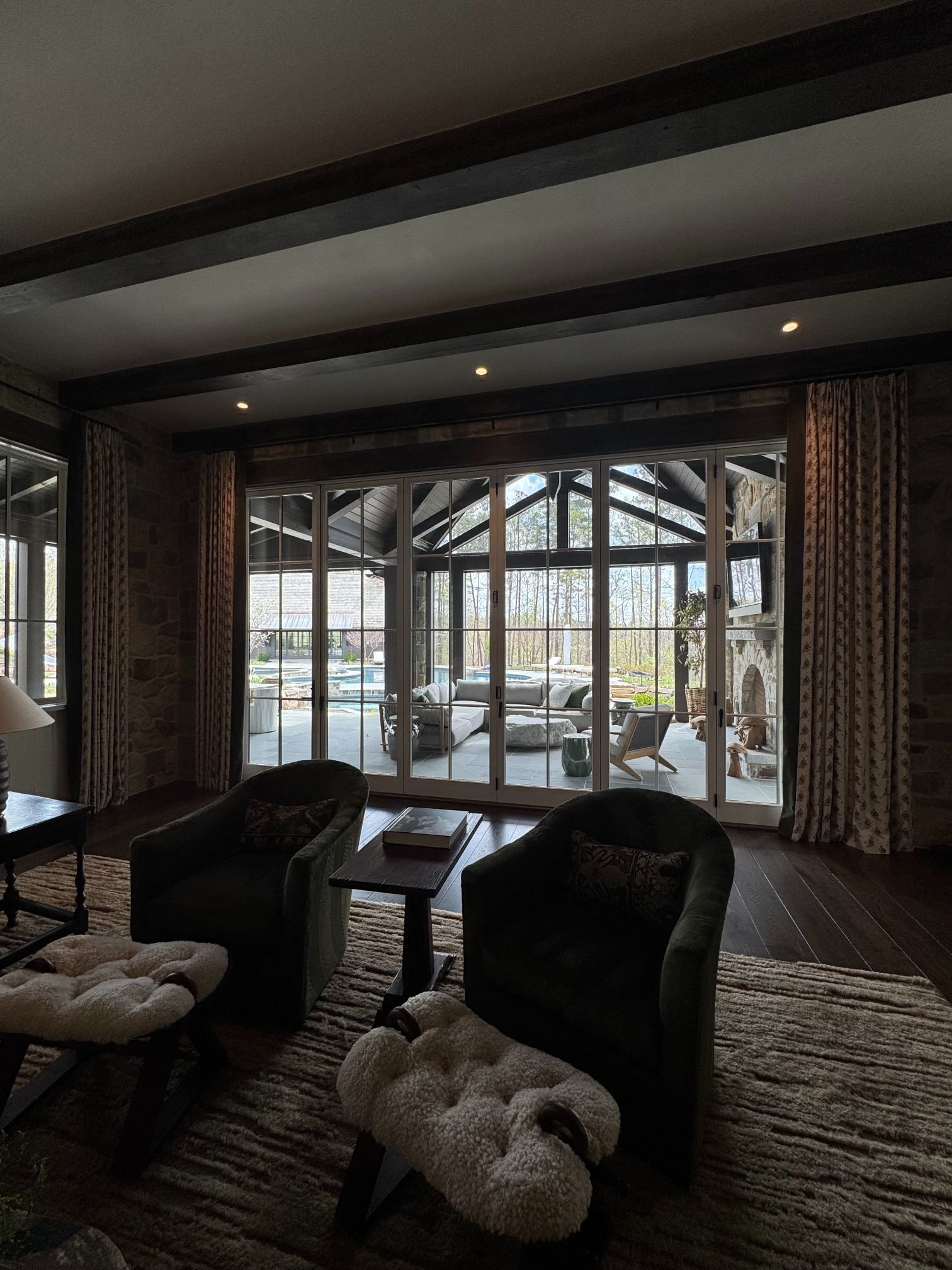 Cozy lounge with armchairs and a coffee table, overlooking a snowy outdoor patio through large windows.
