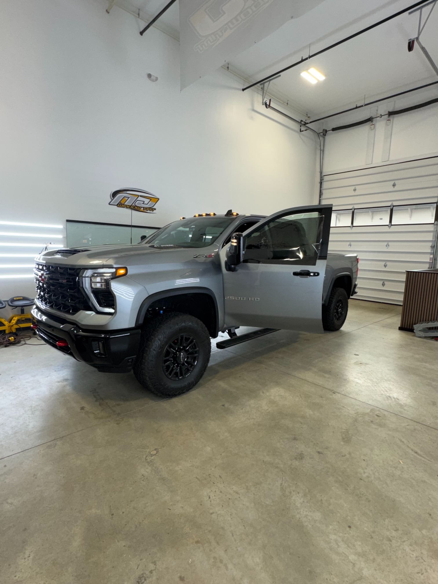 Silver pickup truck parked in a garage with the driver door open