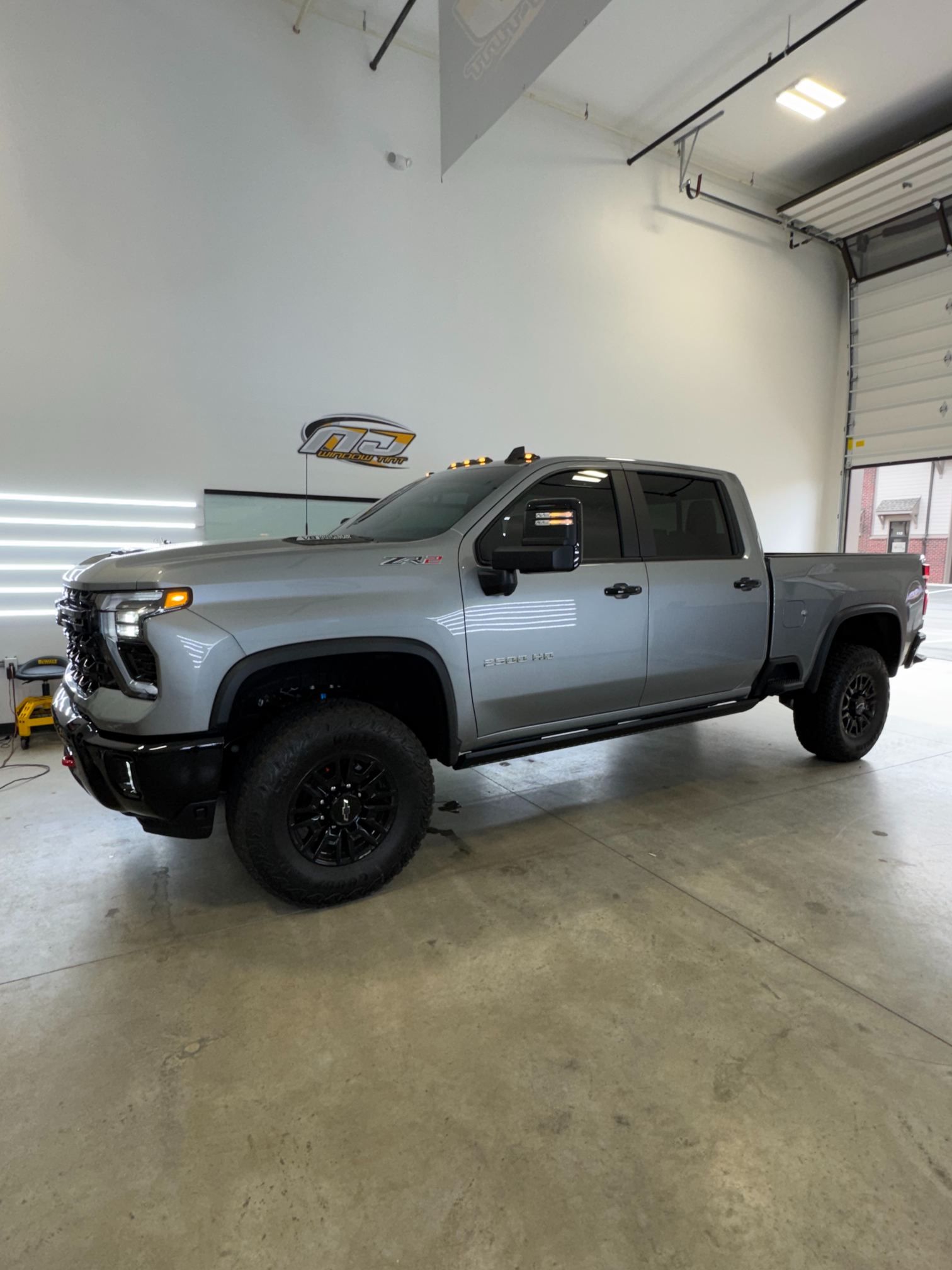 Gray lifted pickup truck parked inside an auto shop garage