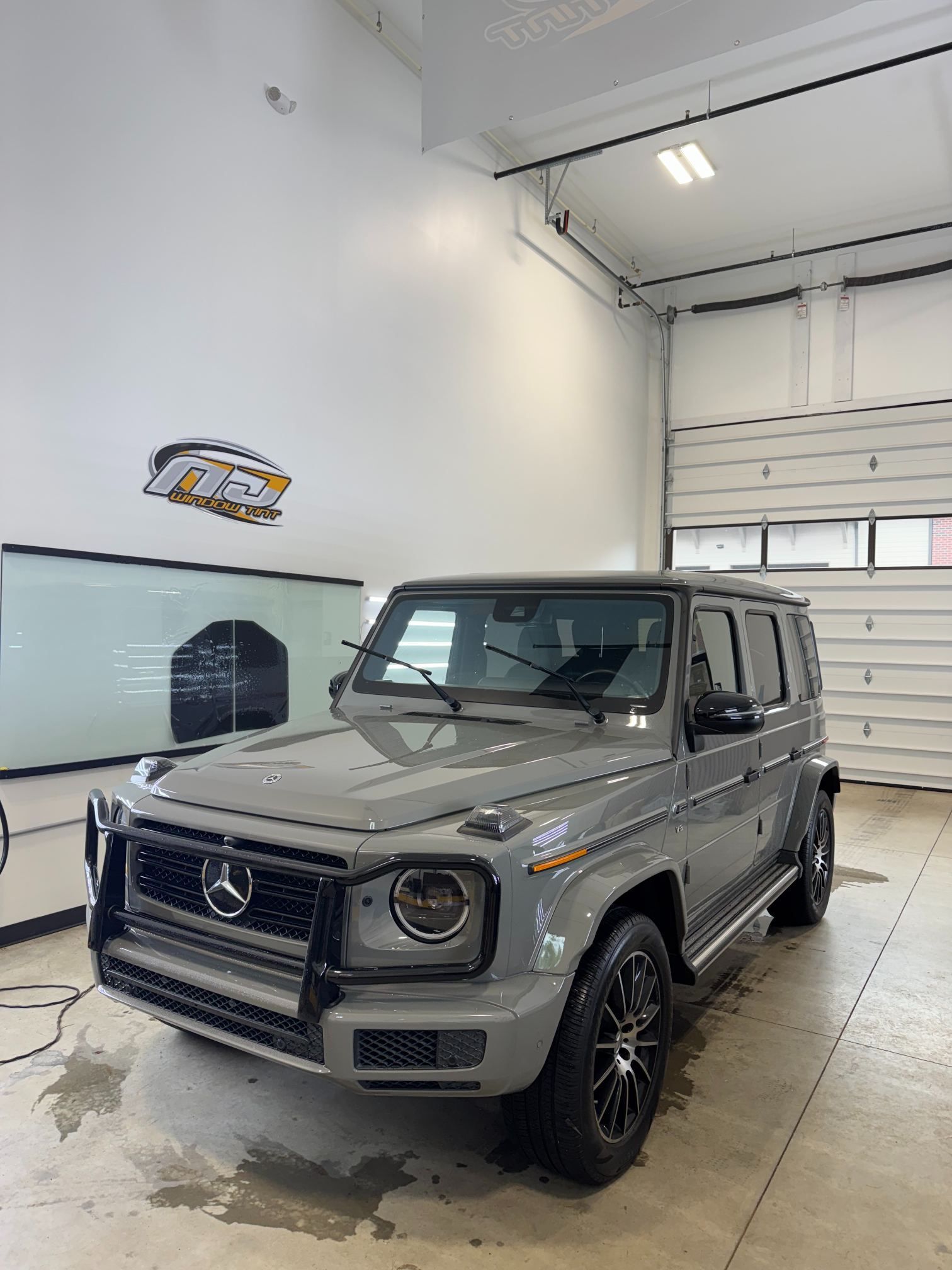 Gray Mercedes G-Class SUV parked in a bright indoor garage, front-left view.