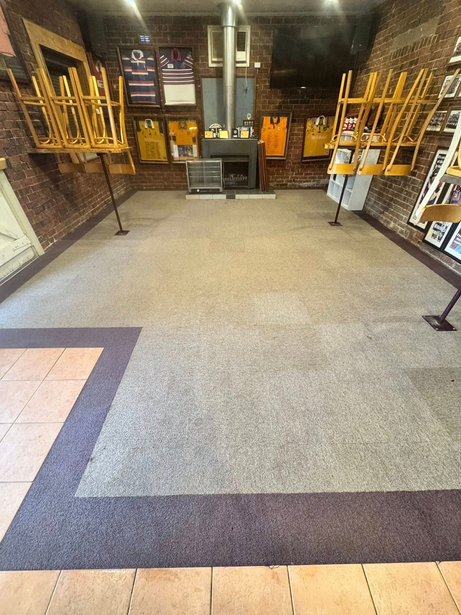 A restaurant dining area with tables pushed aside, grey carpet, brick walls, and jerseys displayed on the back wall — Cobra's Carpet Cleaning in Junee, NSW