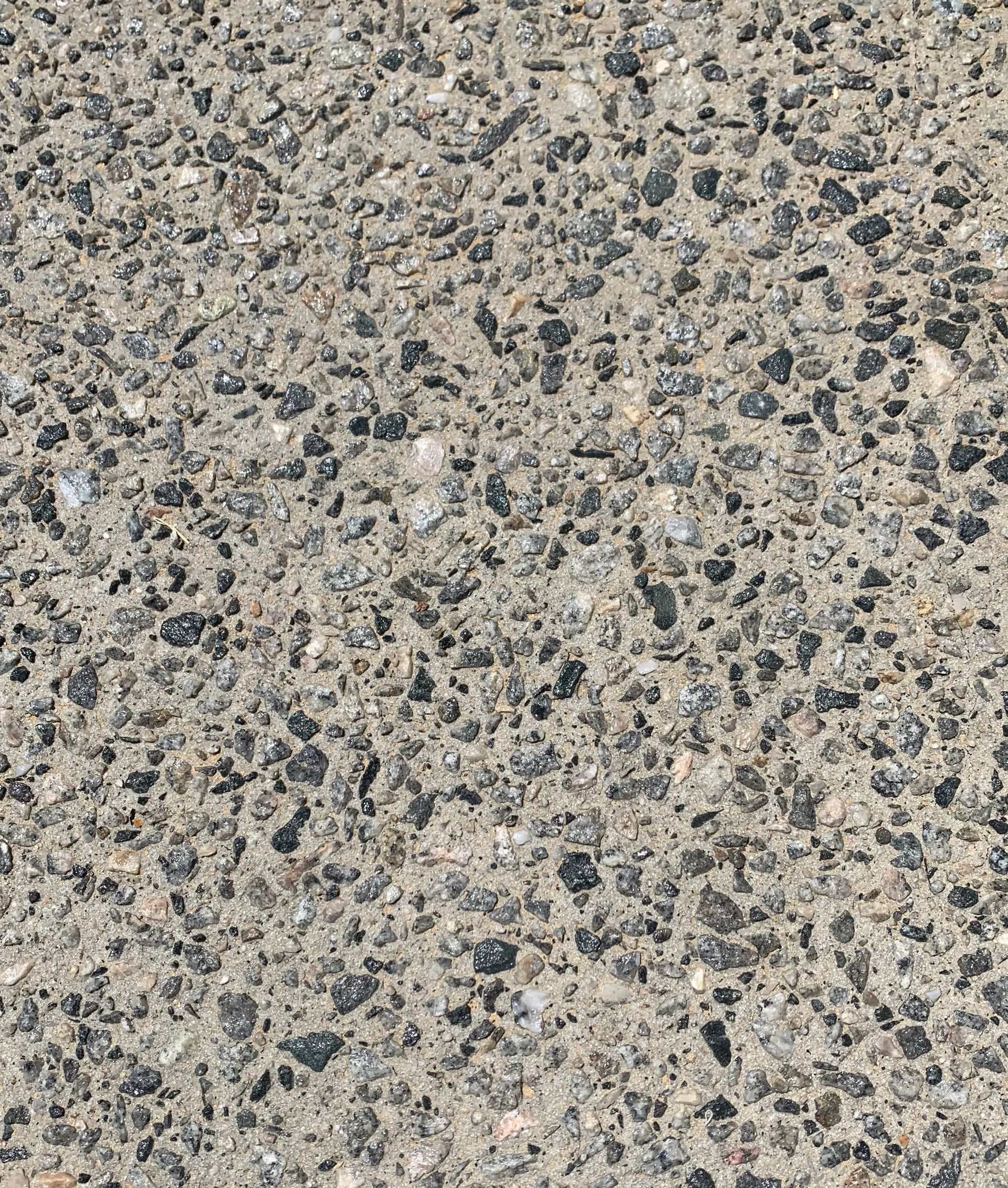 A close up of a grey exposed aggregate driveway finish