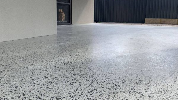 Speckled honed aggregate floor in a spacious, empty alfresco with gray walls rendered walls.