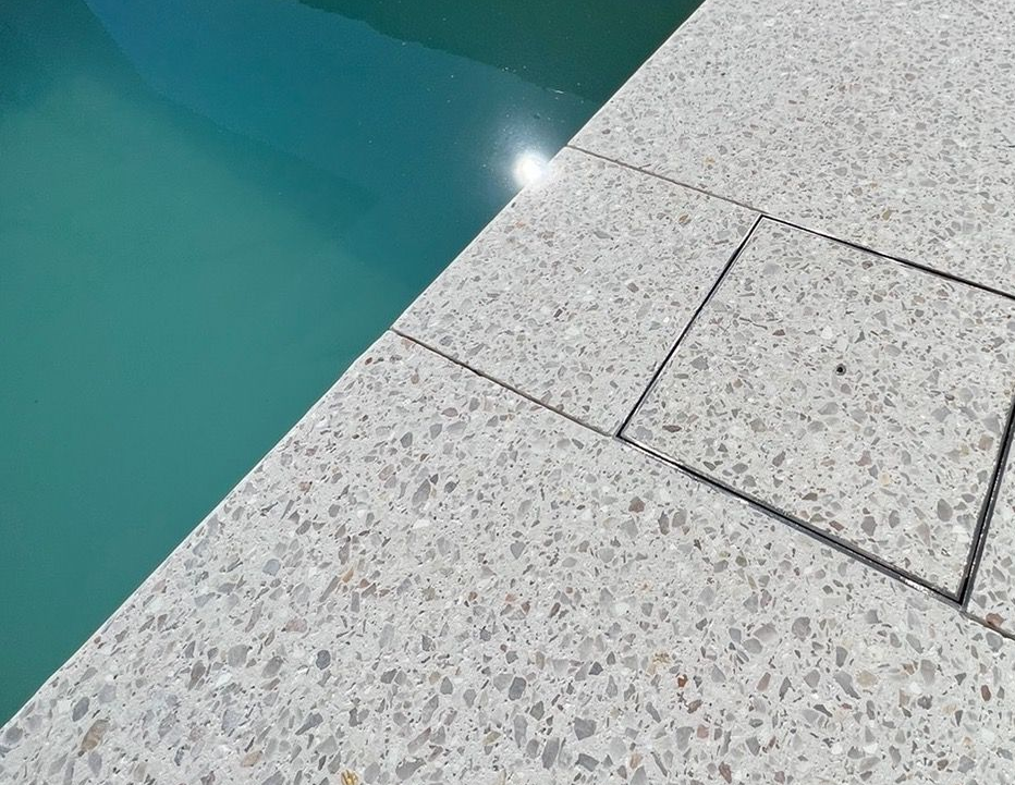 Up close of honed concrete pool surrounds with inset skimmer box