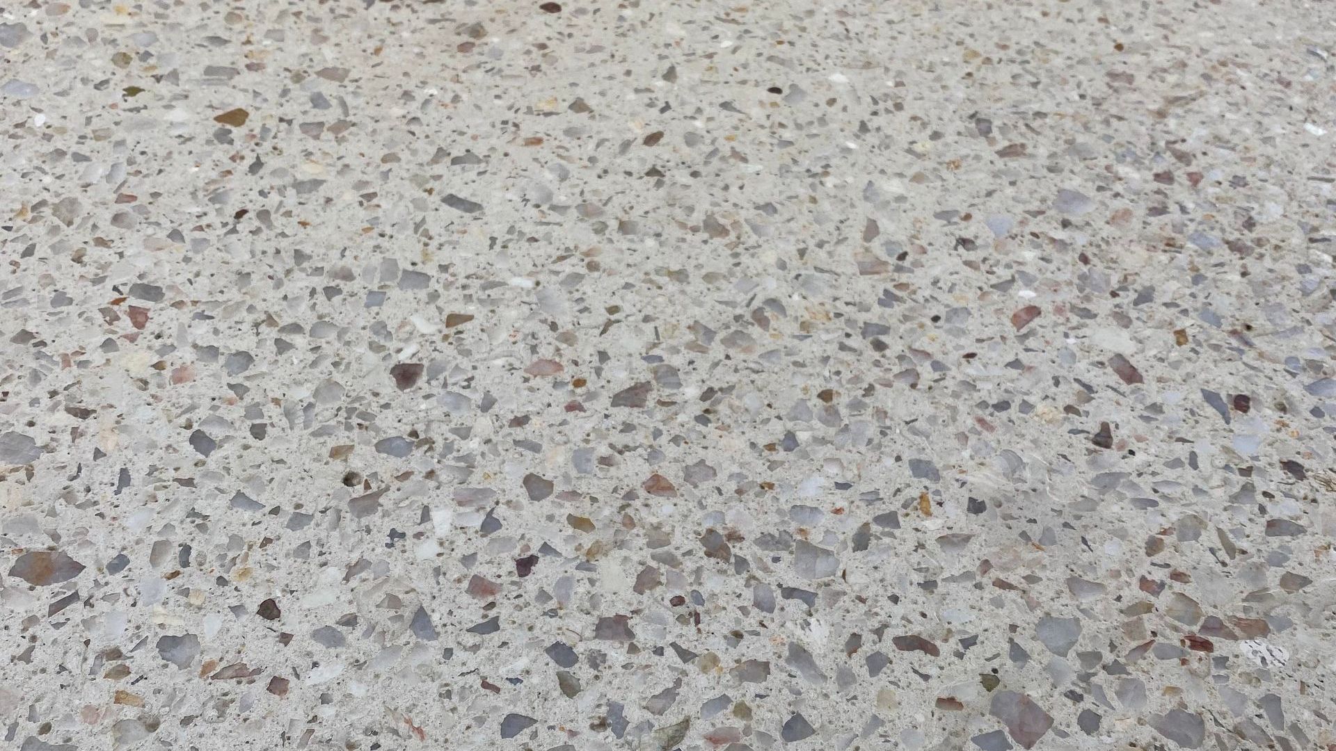 Up close of honed aggregate concrete showing speckled brown and grey aggregates.