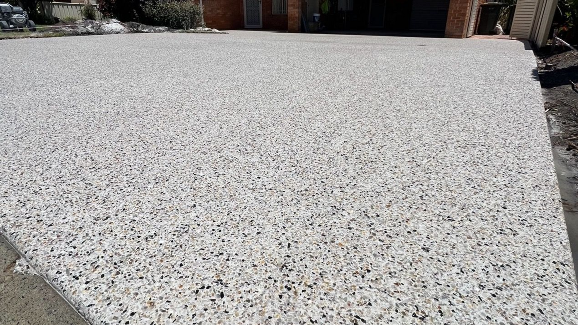Light grey exposed-textured driveway surface in front of a house