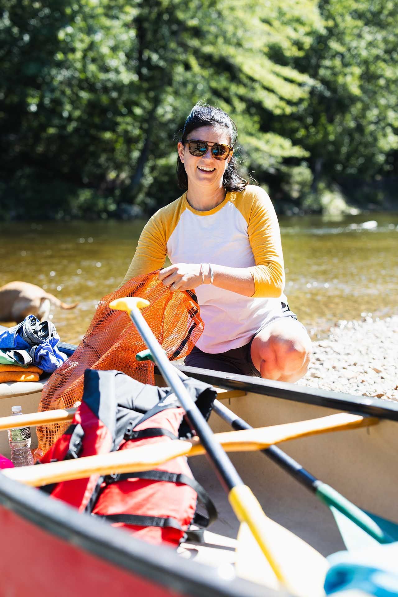 Woman Sitting Beside a Canoe Next to A River
