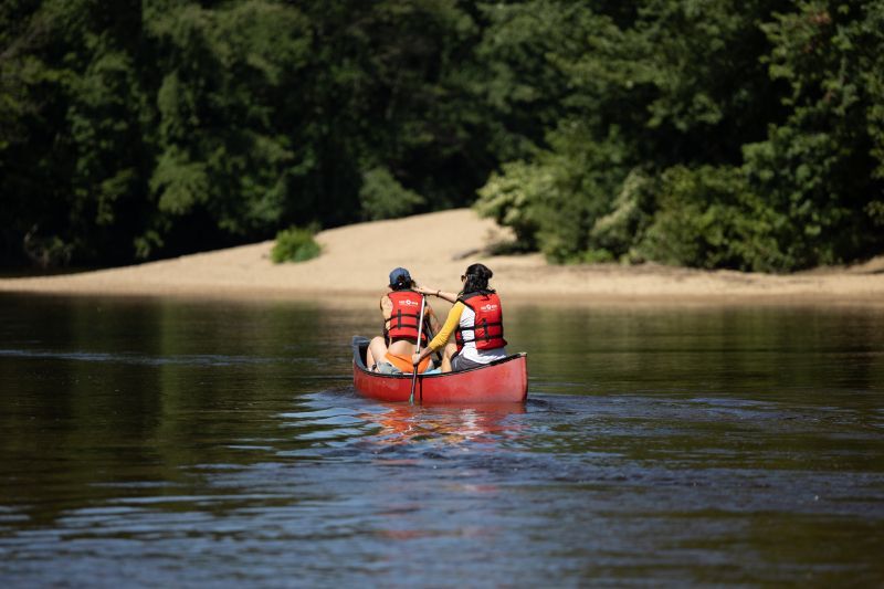 Two people are in a red canoe on a lake.