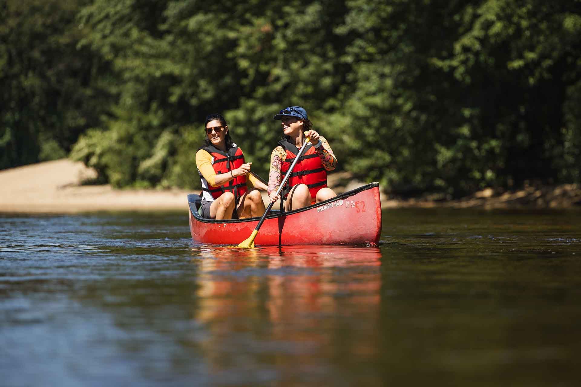 Two People Are Paddling a Red Canoe