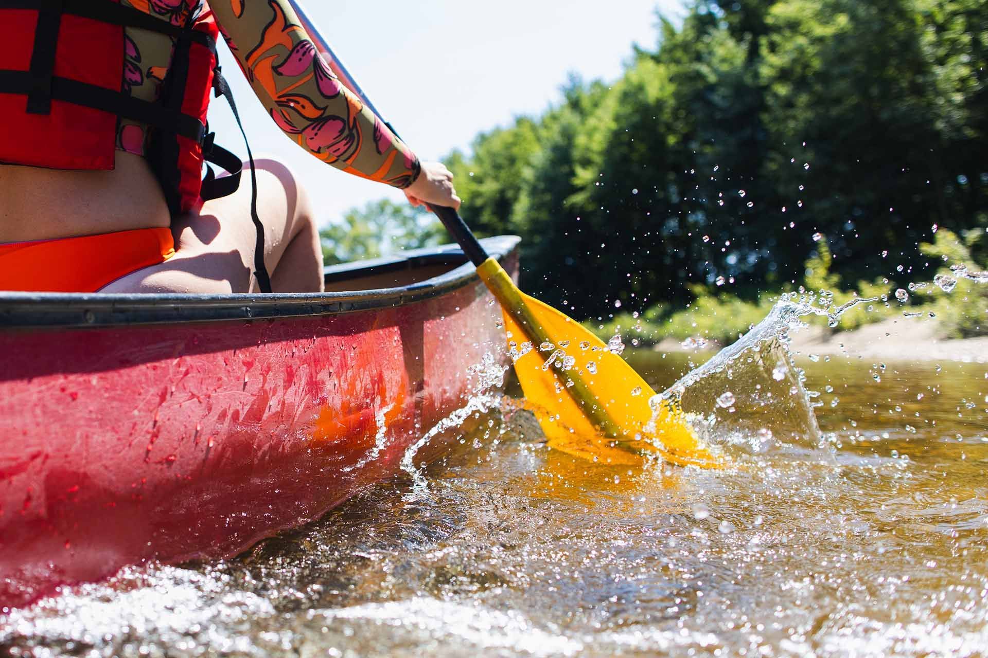 Person Paddling a Red Canoe on A River