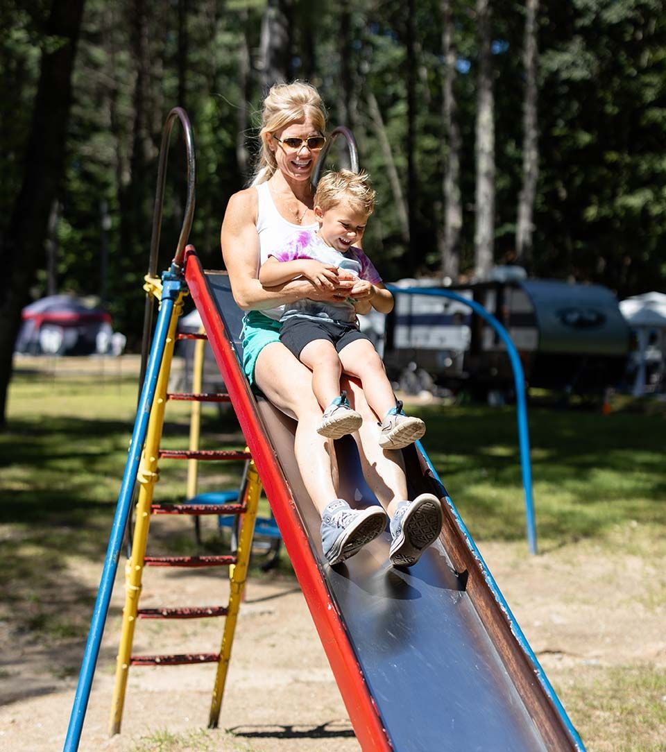 Woman and Child Are Sitting on A Slide at A Playground