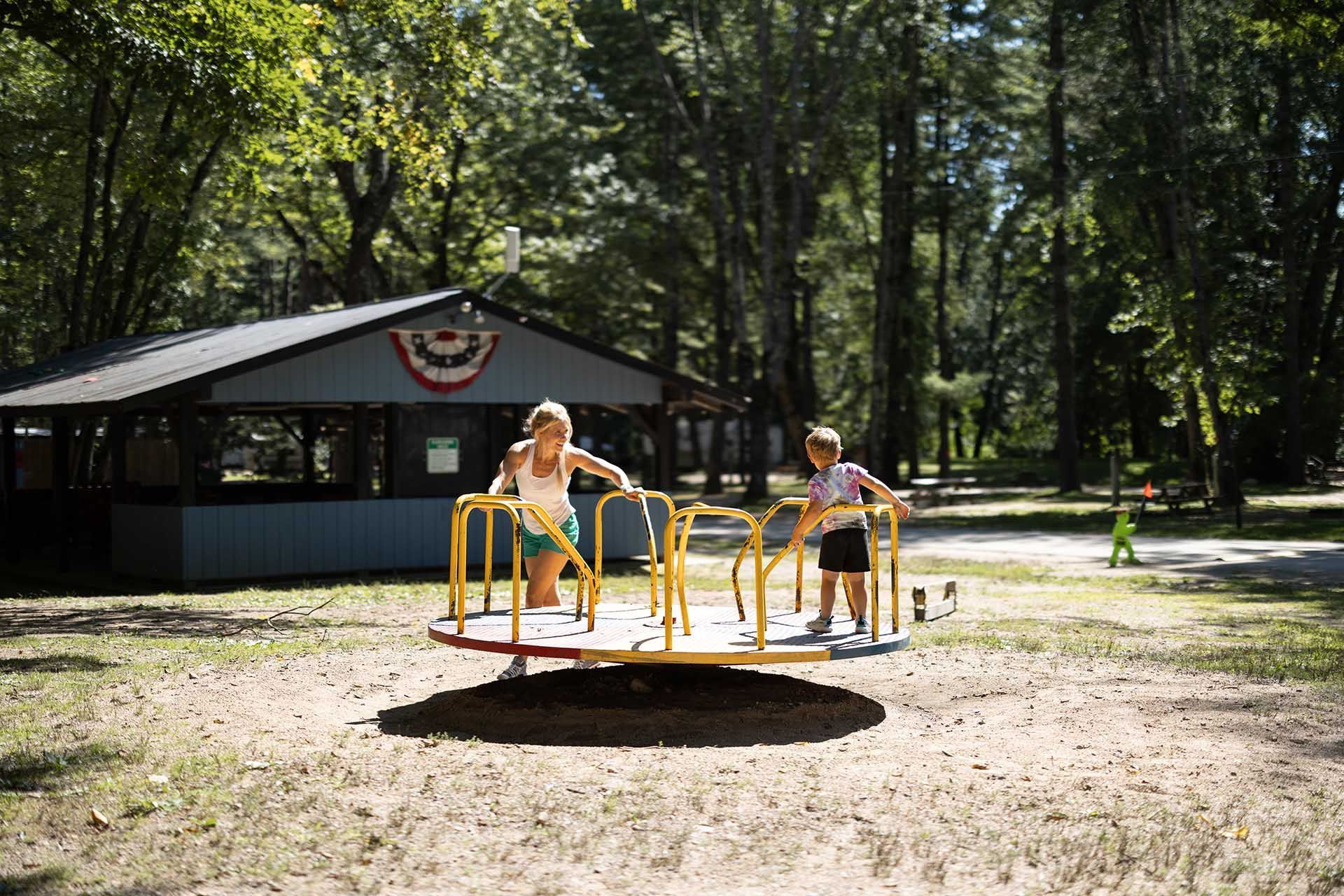 Woman and Kid Are Playing on A Merry Go Round in A Park