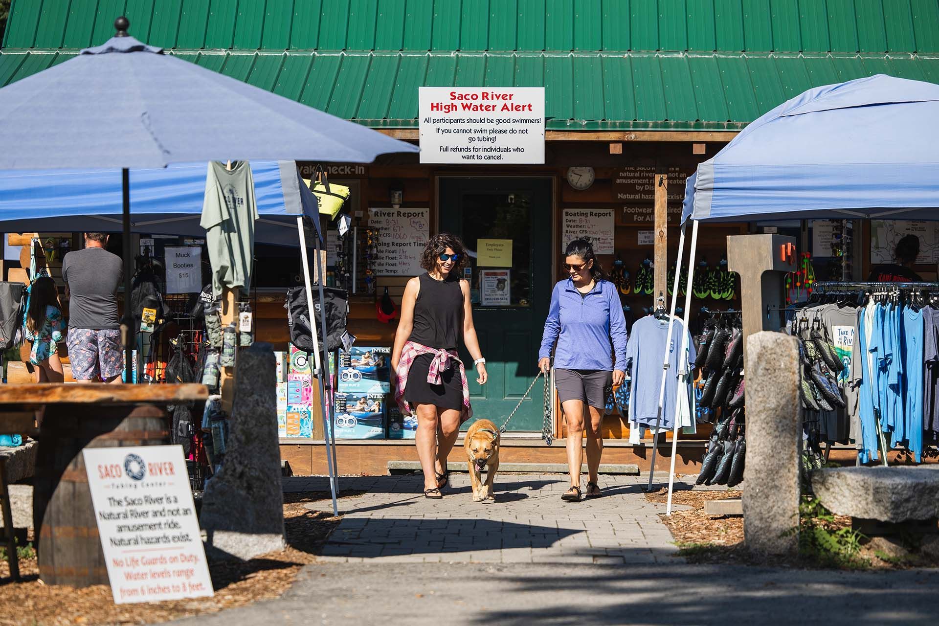two woman and a dog walking out of a store 