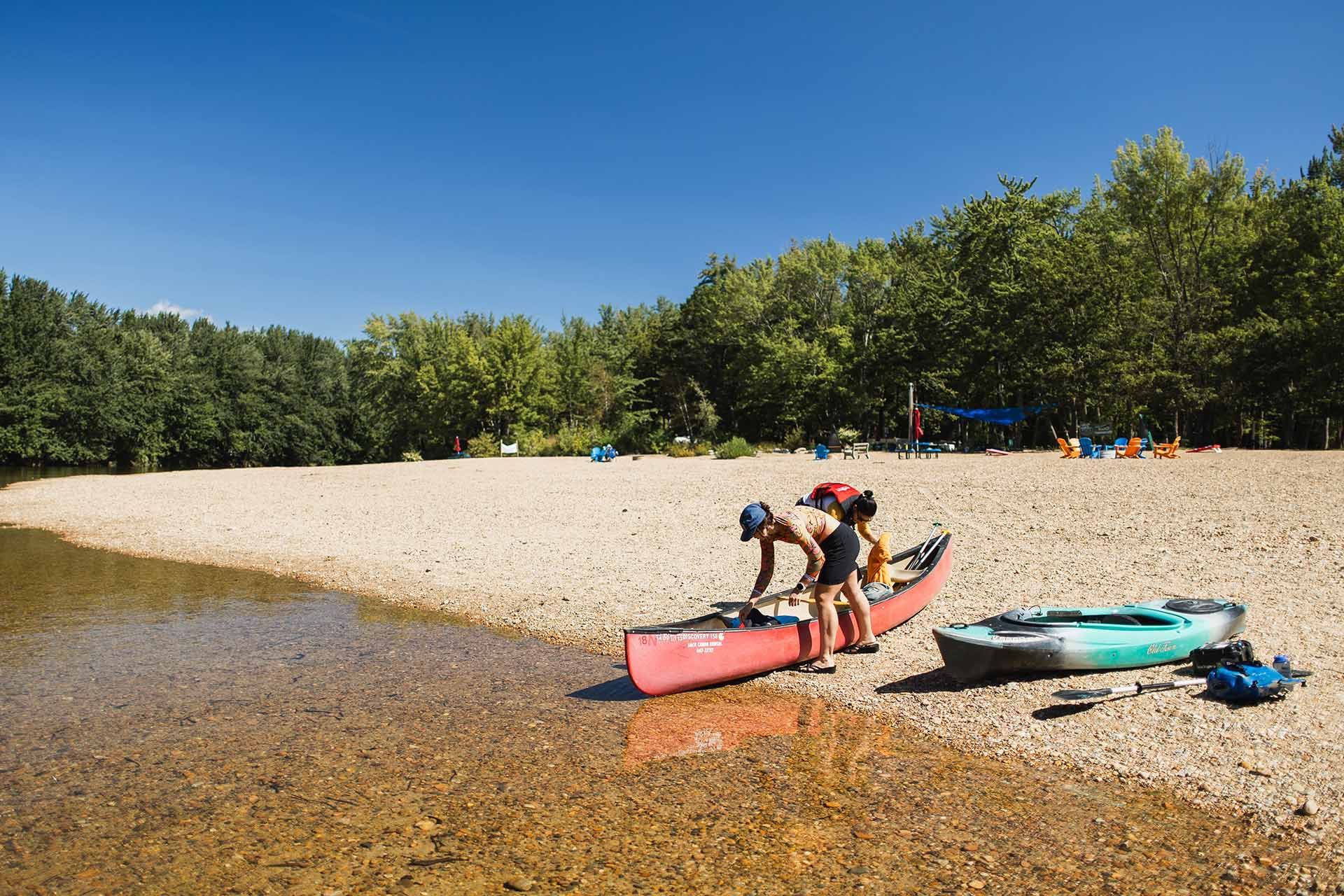 Two People Are Putting a Canoe Into the Water on A River
