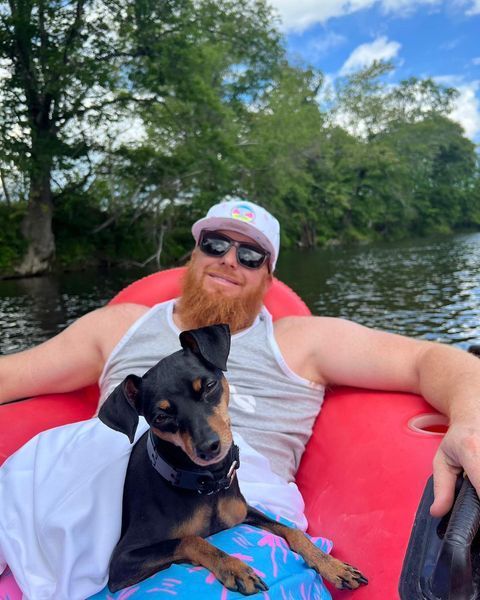 Man and A Dog Are Sitting on A Raft in The Water