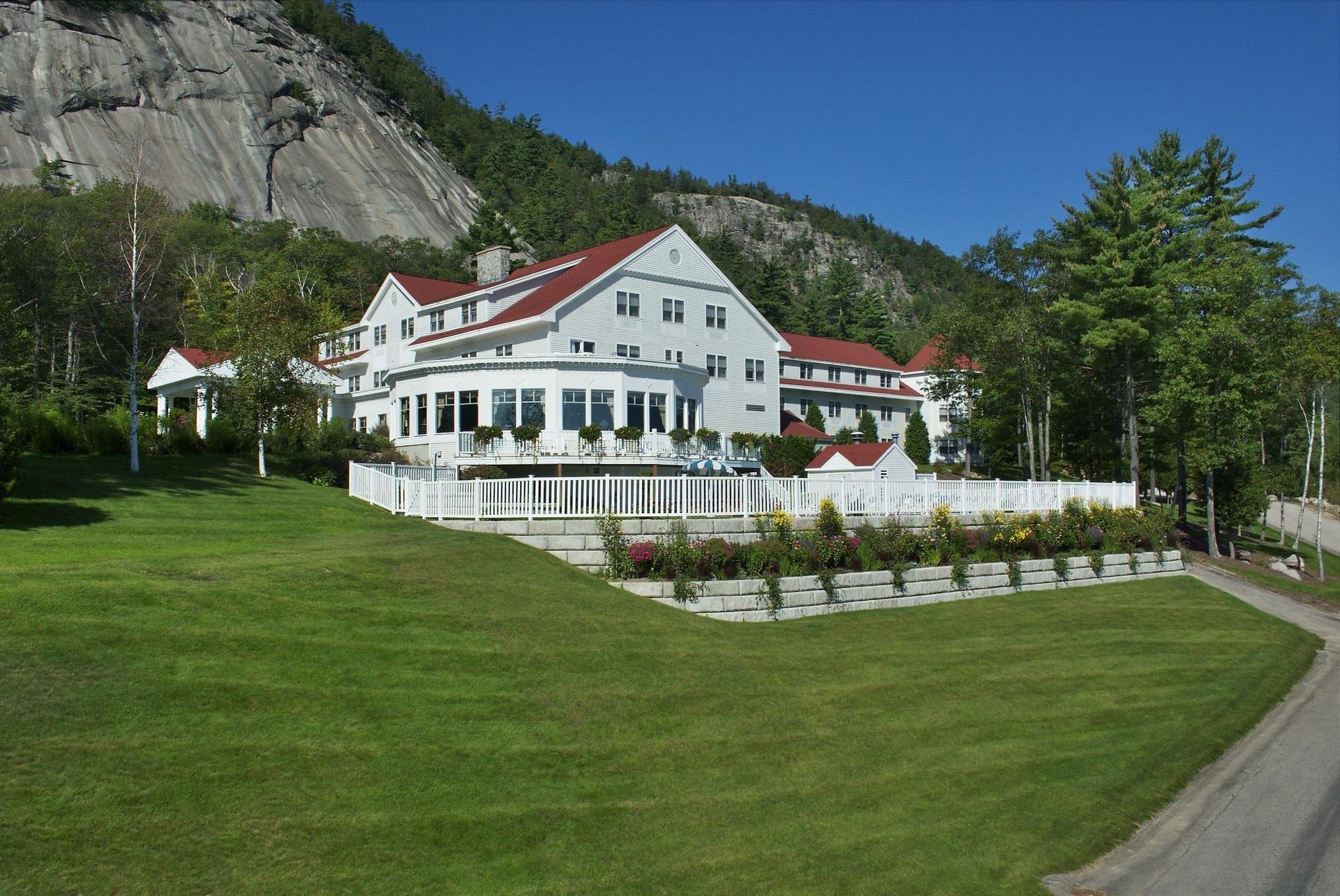 Large White House with A Red Roof Sits on Top of A Lush Green Hillside