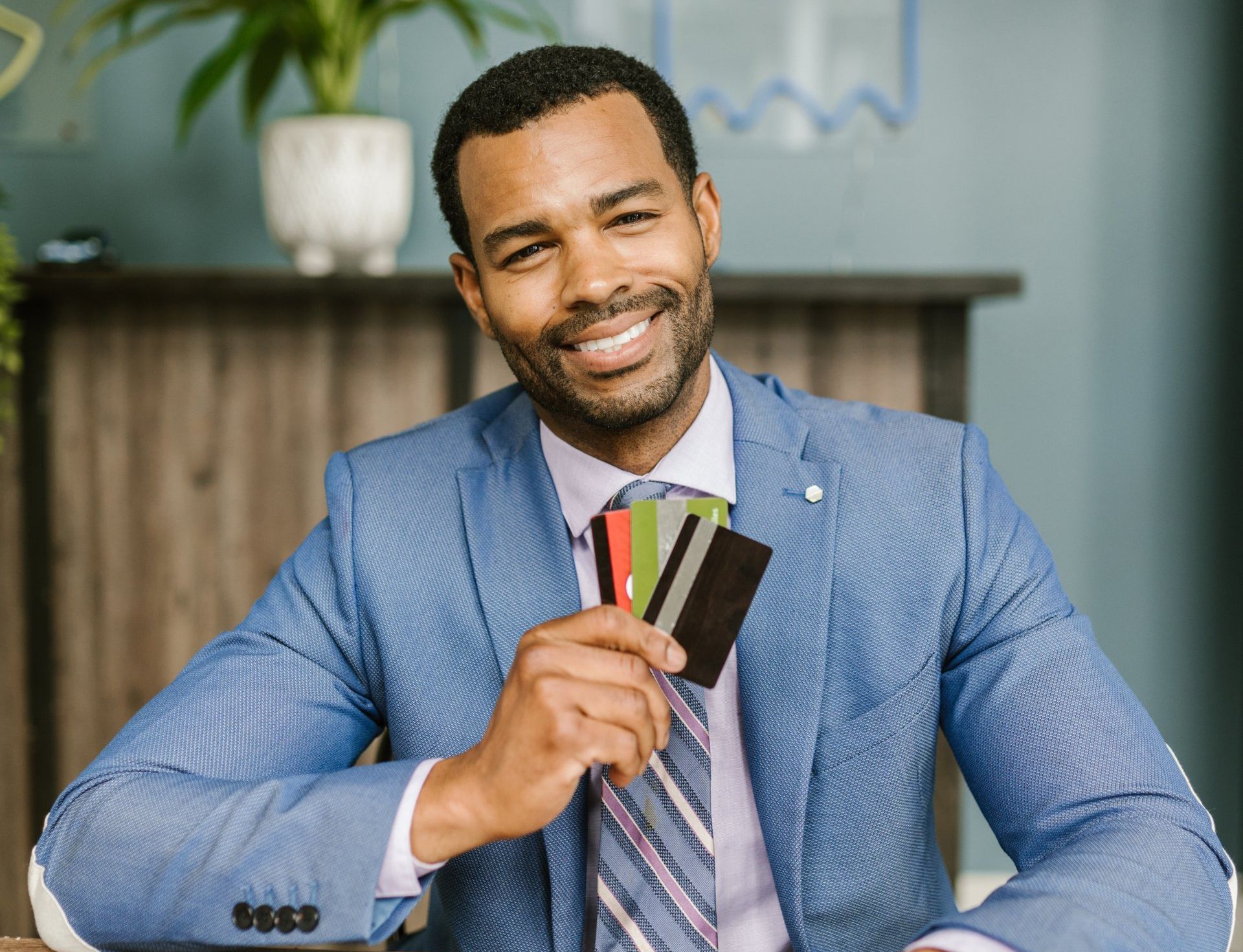 A man in a suit and tie is holding a bunch of credit cards.
