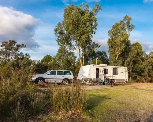 A White SUV is Parked Next to a Trailer in a Field — Capital Caravans Pty Ltd In Raleigh, NSW