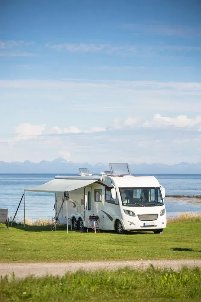 A RV is Parked in a Grassy Field Next to the Ocean — Capital Caravans Pty Ltd In Nambucca Heads, NSW