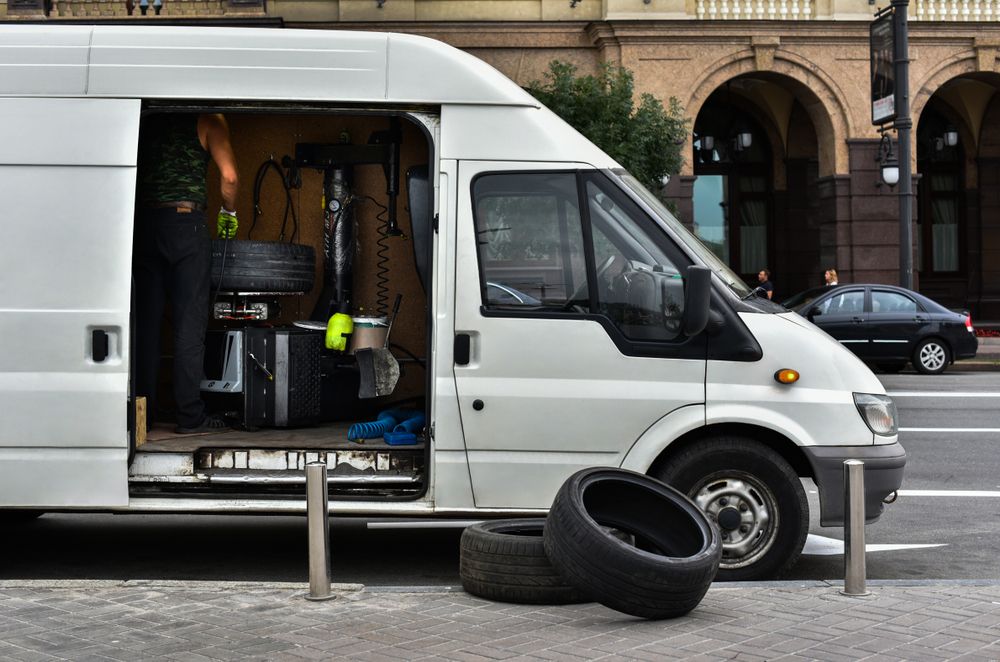 A White Van With Tires in the Back is Parked on the Side of the Road — Capital Caravans Pty Ltd In South West Rocks, NSW