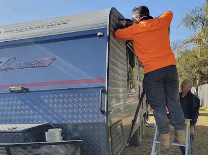 A Man is Standing on a Ladder Next to a Camper Van — Capital Caravans Pty Ltd In Grafton, NSW