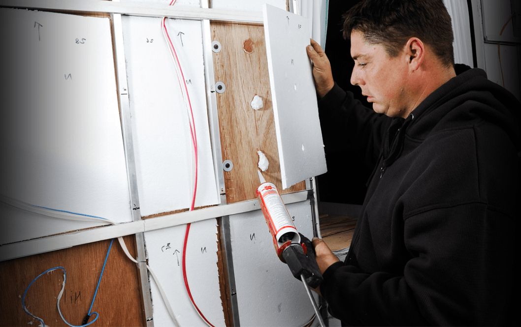 A Man is Applying Silicone to a Wall — Capital Caravans Pty Ltd In Raleigh, NSW