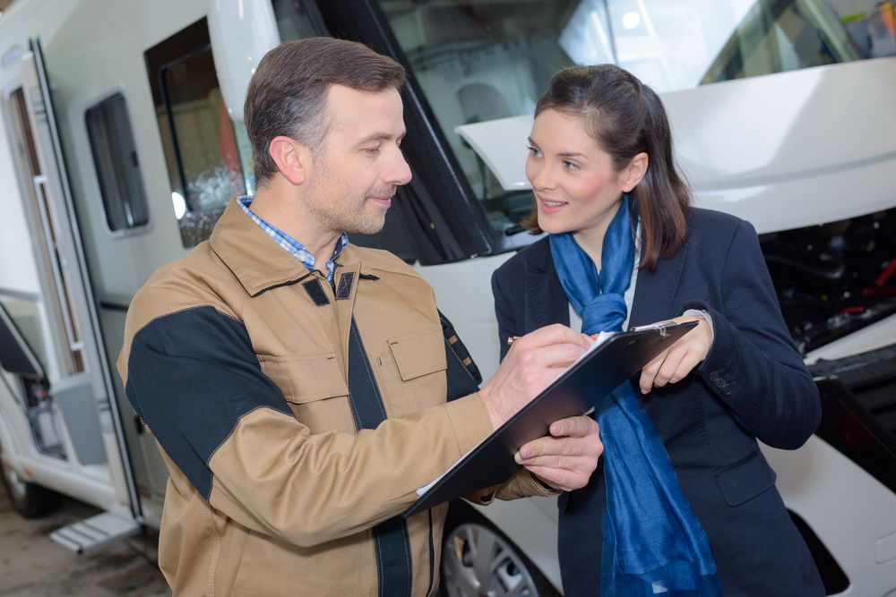 A Man and a Woman Are Looking at a Clipboard in Front of a Camper Van — Capital Caravans Pty Ltd In South West Rocks, NSW